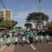 Crianças e adultos de mãos dadas participam de desfile em Dourados, com público nas laterais da avenida. Foto de arquivo.
